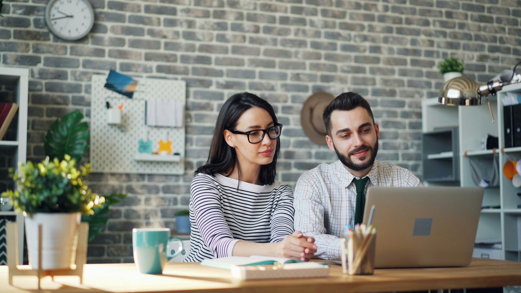 Two colleagues at a desk reviewing something together on a laptop